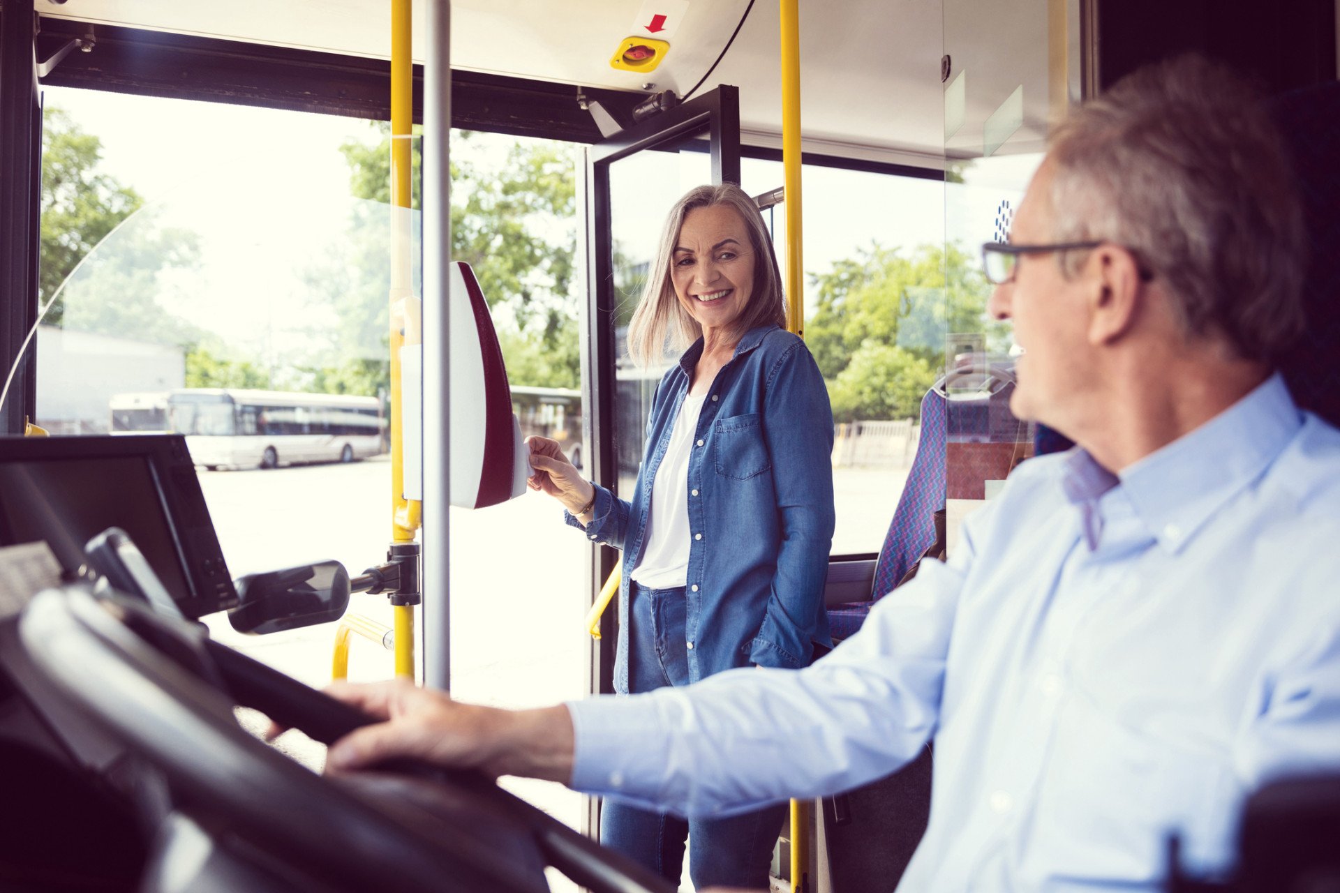 Fahrgast im Bus und Busfahrer schauen sich lächelnd an